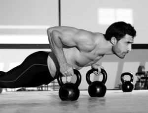 Hombre haciendo flexiones con kettlebells.