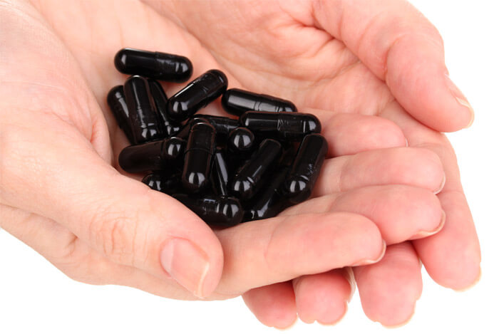 hands holding charcoal capsules