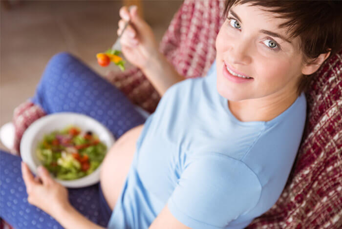 pregnant woman eating on couch