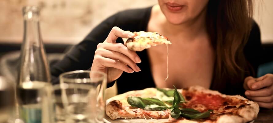 woman-holds-sliced-pizza-seats-by-table-with-glass-723031-1.jpg