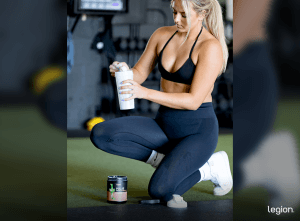 Female athlete mixing Pulse pre-workout before a leg day workout for women