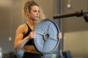 Female athlete loading plates to get ready for a leg and butt workout for women