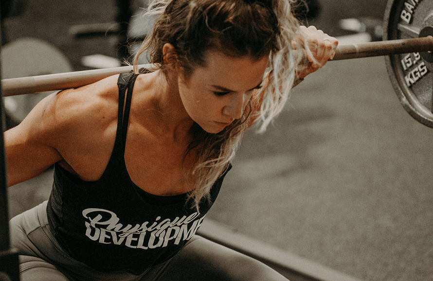 Female athlete following a workout routine for women involving heavy compound weightlifting.