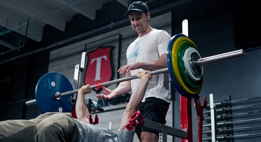 Mike Matthews setting up for the dumbbell bench press to illustrate why some people ask whether dumbbell bench press is better than barbell.
