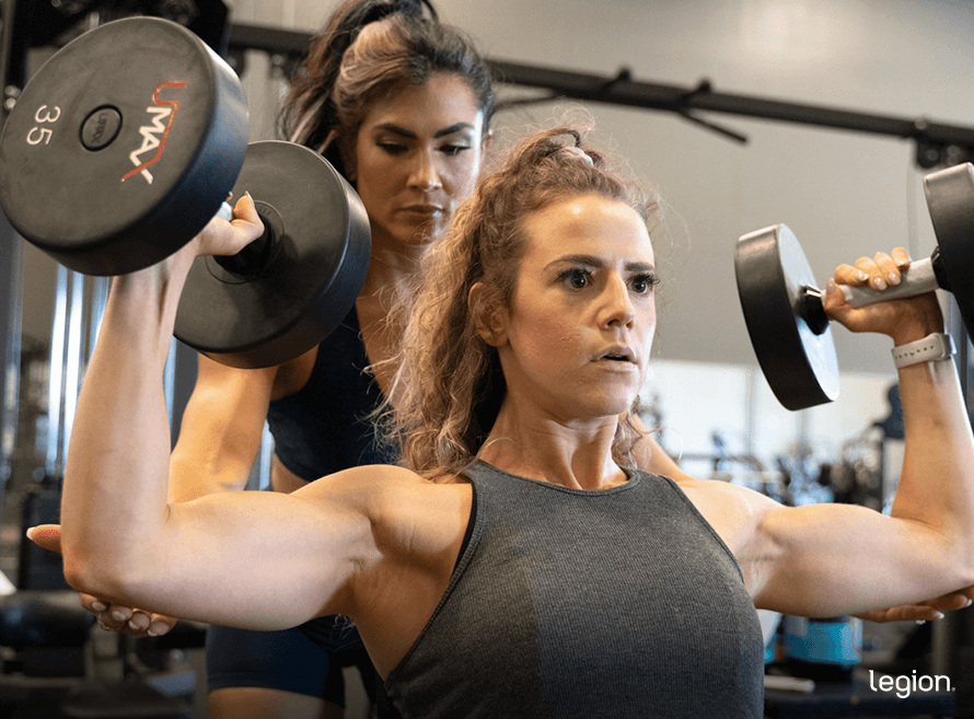 Woman doing a shoulder press in a gym during a flabby arm exercises workout