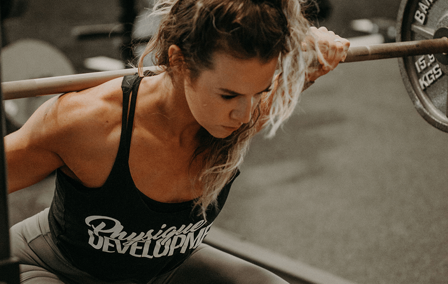 Female athlete squatting with a barbell to train the inner thighs, glutes, and quads