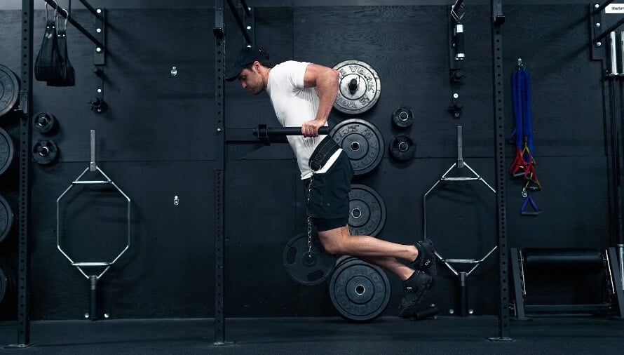 Man performing weighted dips on parallel bars to train chest and triceps.