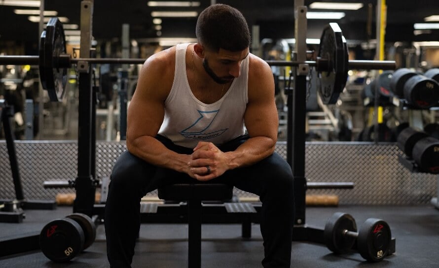 Gymgoer sitting on the edge of a bench between sets, representing resting and deciding how long after eating to work out.