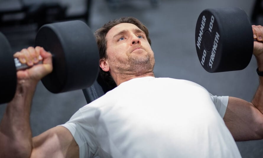 Man doing an incline dumbbell bench press for upper chest and triceps development.