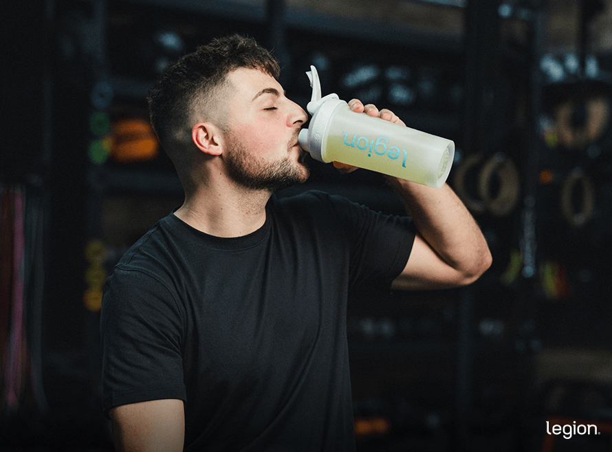 Male athlete drinking from a shaker bottle after training, highlighting whether creatine HMB supplements work better than creatine alone.