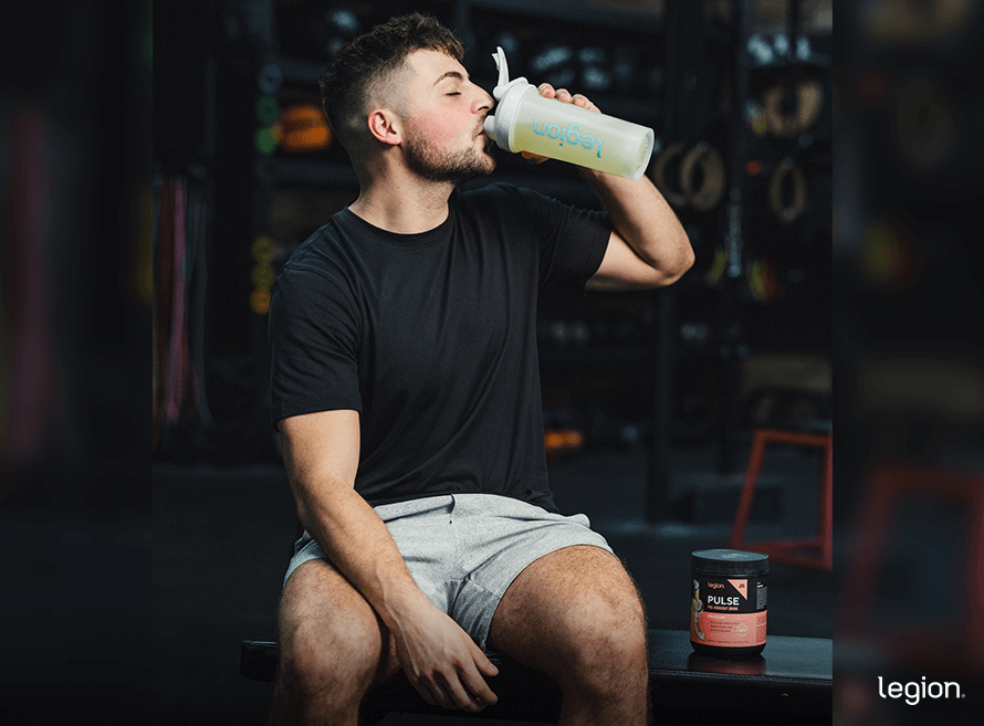 Male beginner lifter drinking pre-workout 30 minutes before strength training.