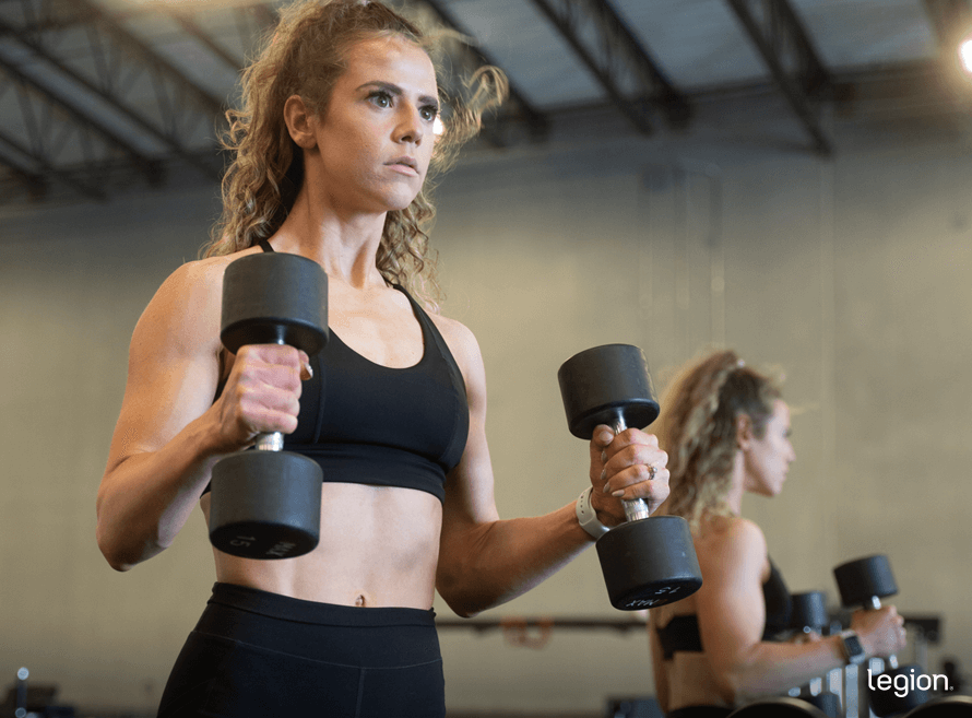 Female athlete doing hammer curls in the gym as part of a body recomposition workout plan for females.