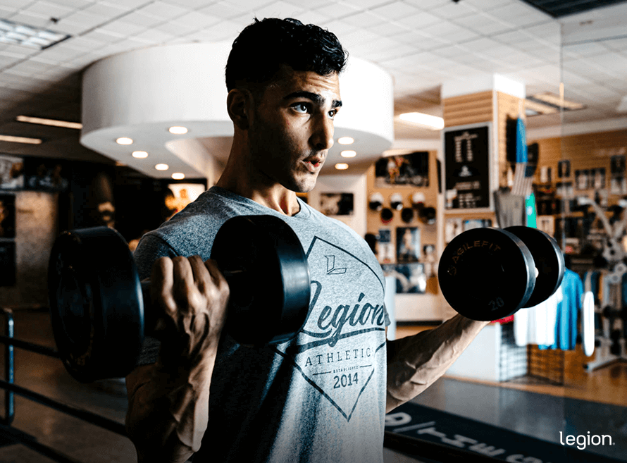 Male athlete performing dumbbell biceps curls during a high-intensity Doggcrapp training workout