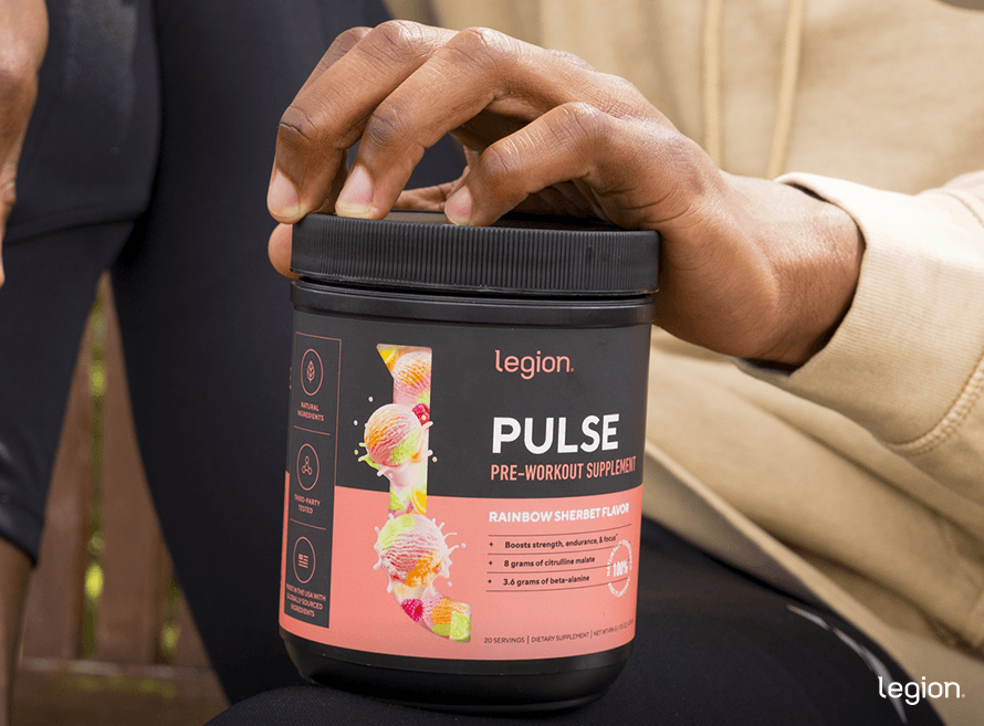 Athlete holding tub of pre-workout, checking the label to see if it contains calories.