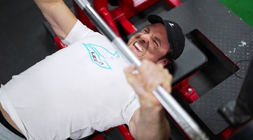 Male athlete doing the bench press at the beginning of a chest and back workout routine for mass.