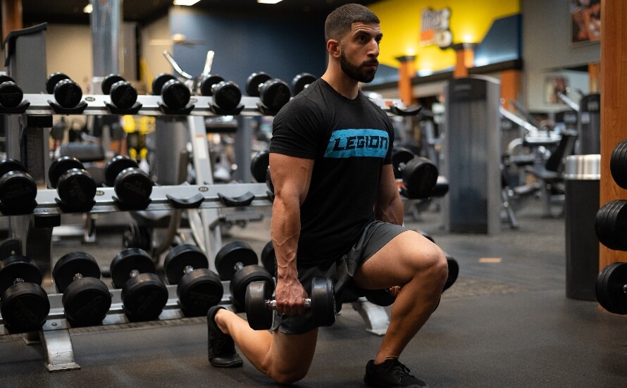 Male athlete pefroming lunges in the gym as part of the PHUL 4-day split workout routine.