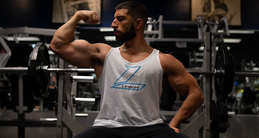 Male athlete flexing in the gym, showing his size gains made on the PHUL workout program