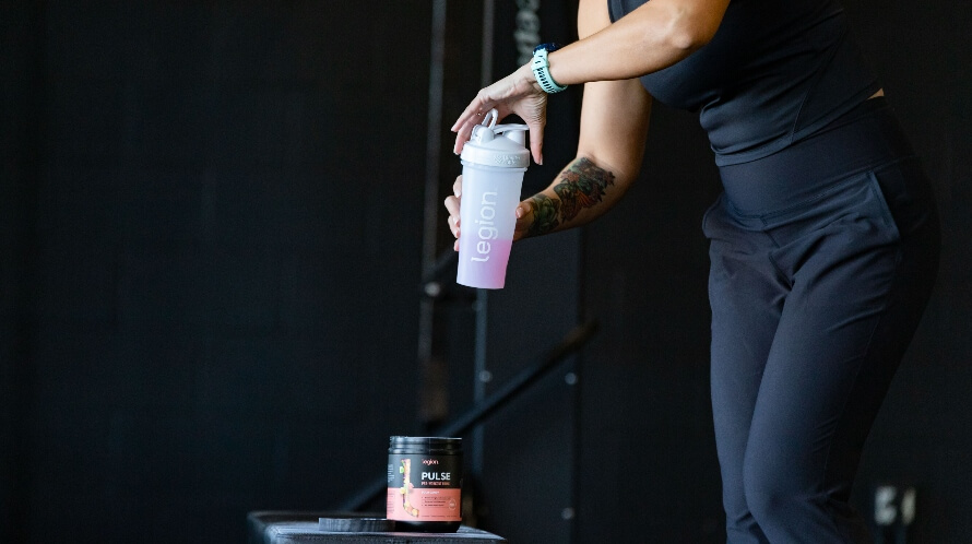 Female athlete in the gym making a pre-workout in a shaker bottle, illustrating pre-workout for wopemn can help boost performance.