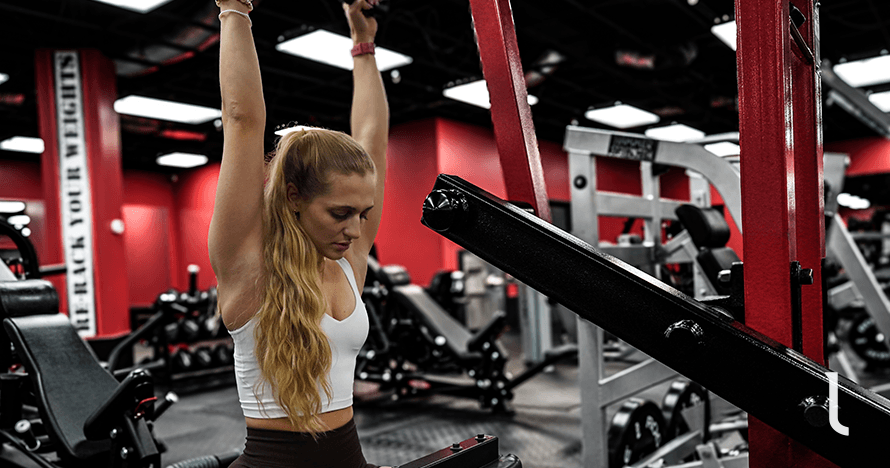 Female athlete doing a lat pulldown as part of a arm and back workout for women.