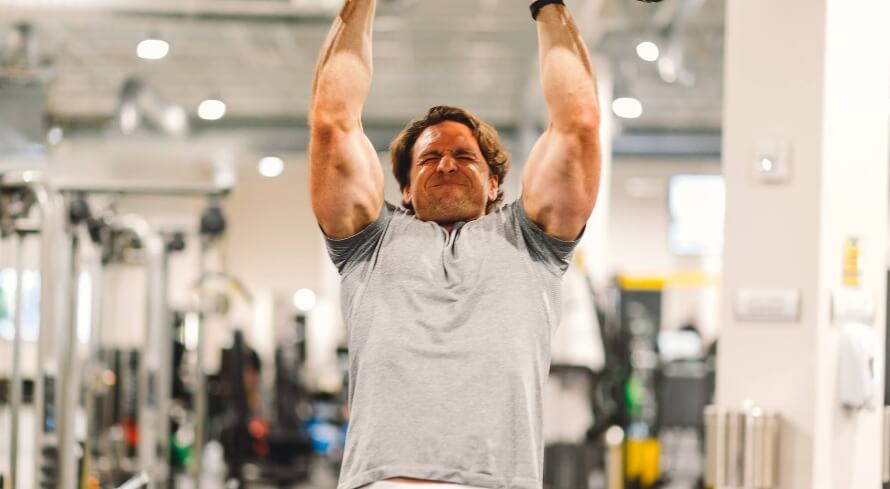 Male athlete doing neutral-grip pull-ups as part of a rear delt workout.