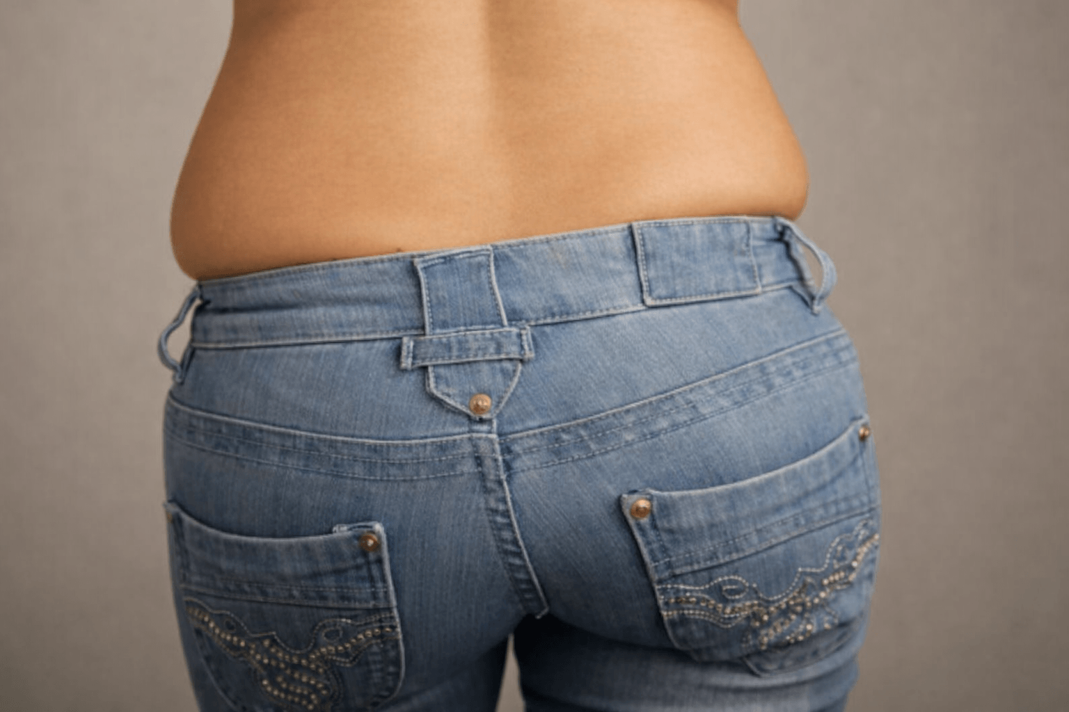 Image of woman in jeans with visible muffin top around her waistband.