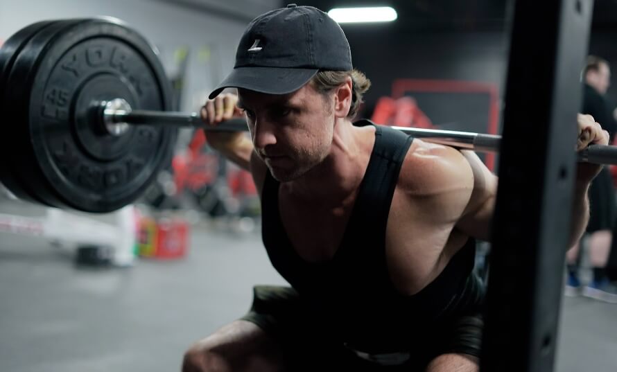 Male athlete back squatting in a leg workout as part of a PPLUL workout plan.