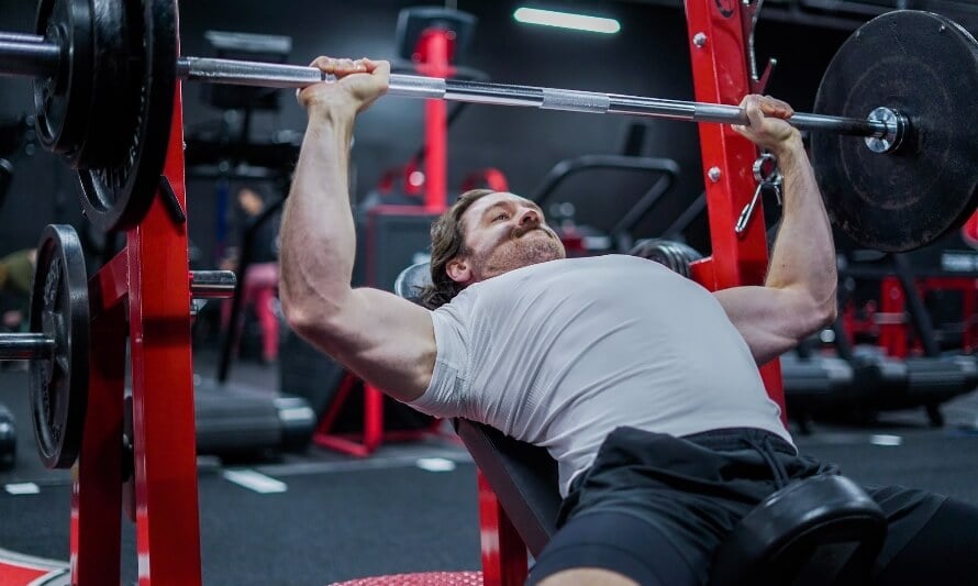 Male athlete doing the incline barbell bench press while following a ULPPL split.
