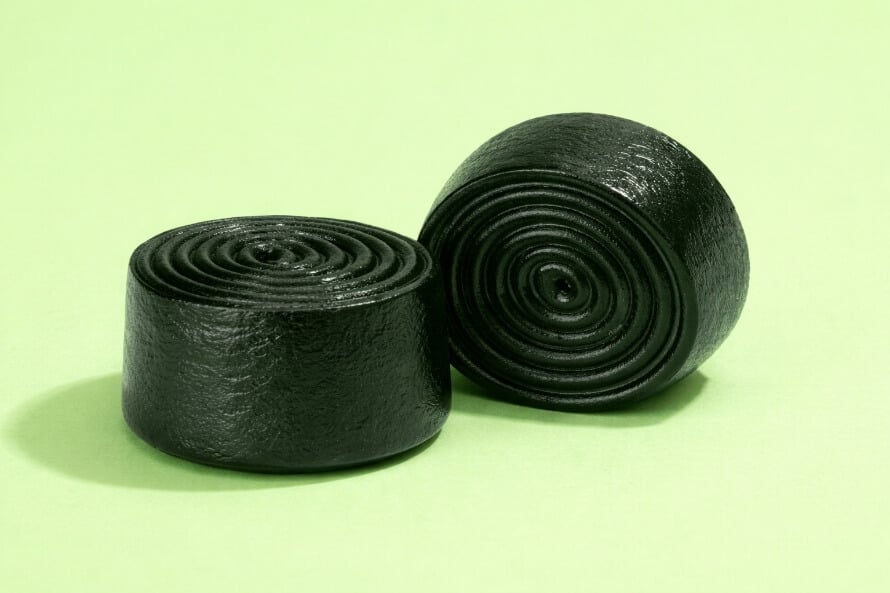 Close-up of two dark greens gummies with spiral-shaped top.