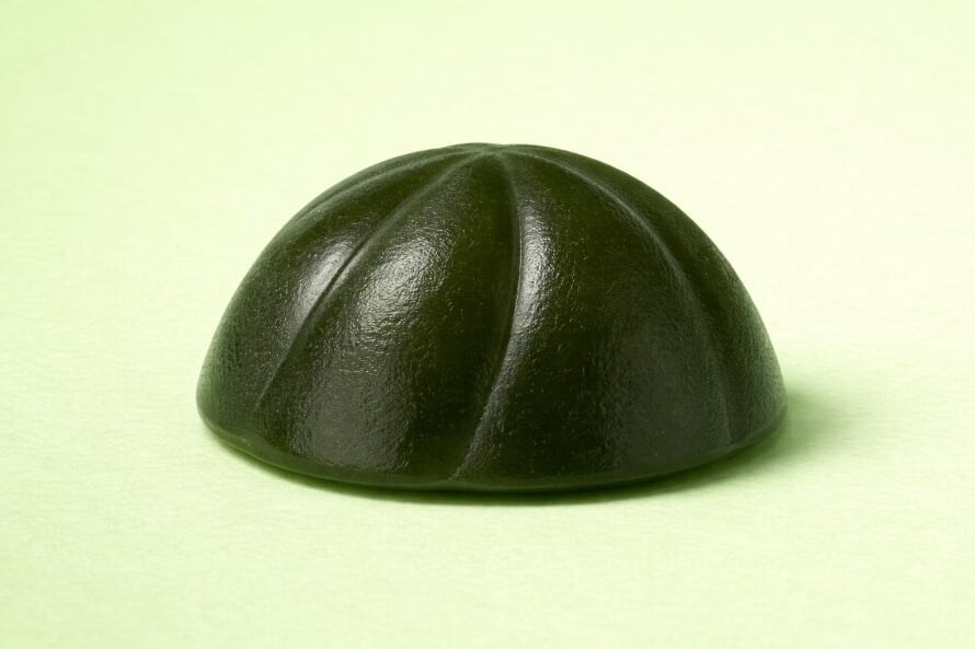 Close-up image of a dark greens gummies with a segmented dome-shaped top.