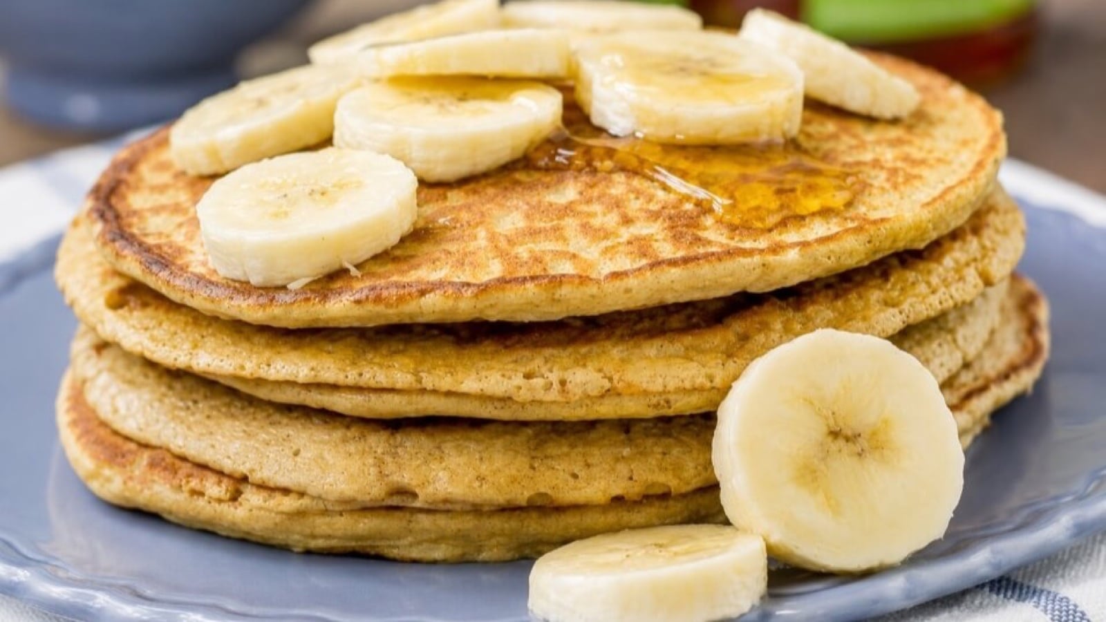 A stack of cottage cheese pancakes topped with banana slices and syrup