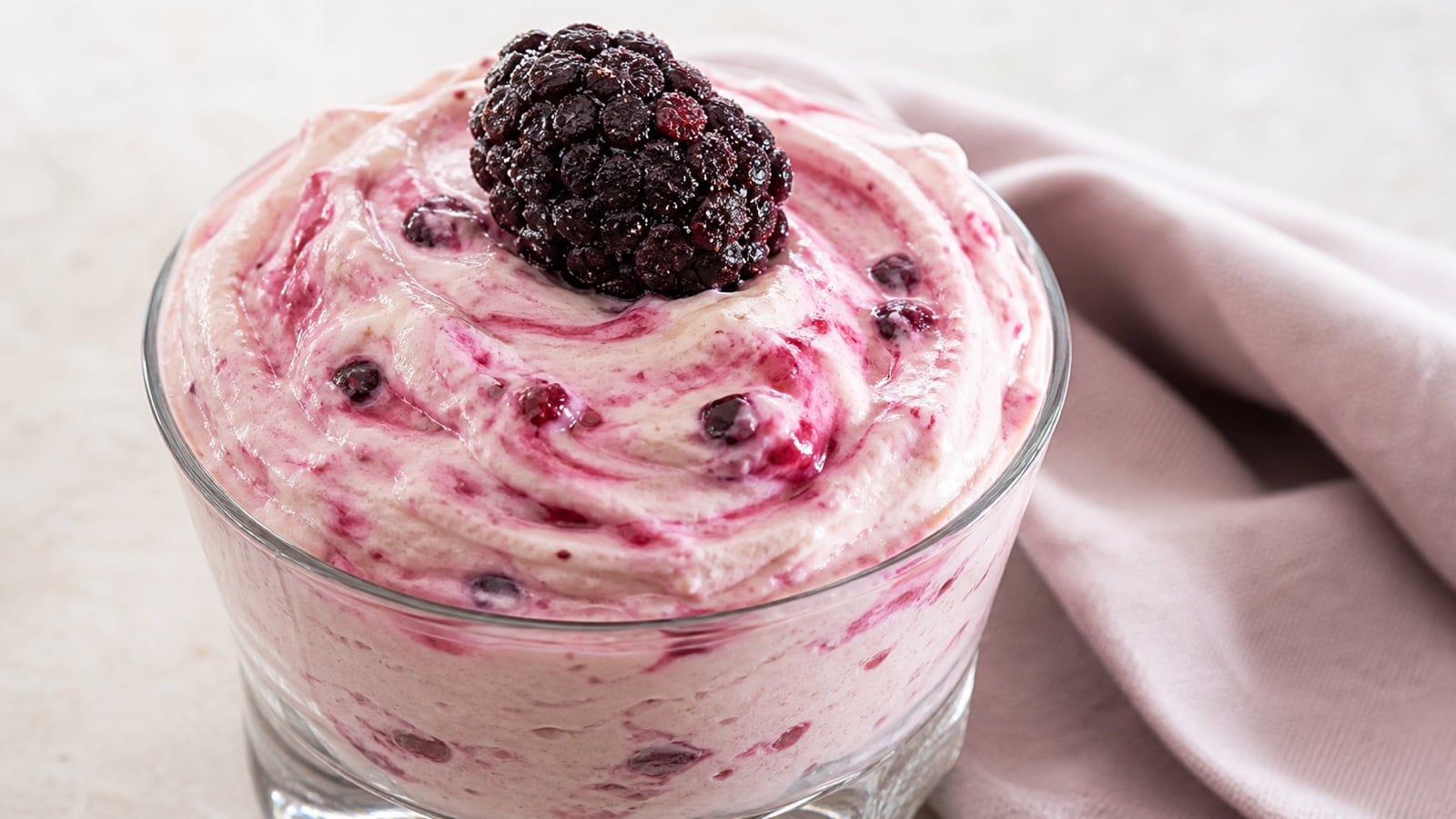 Close glass of pale pink cottage cheese berry mousse showing its creamy texture and berry flecks