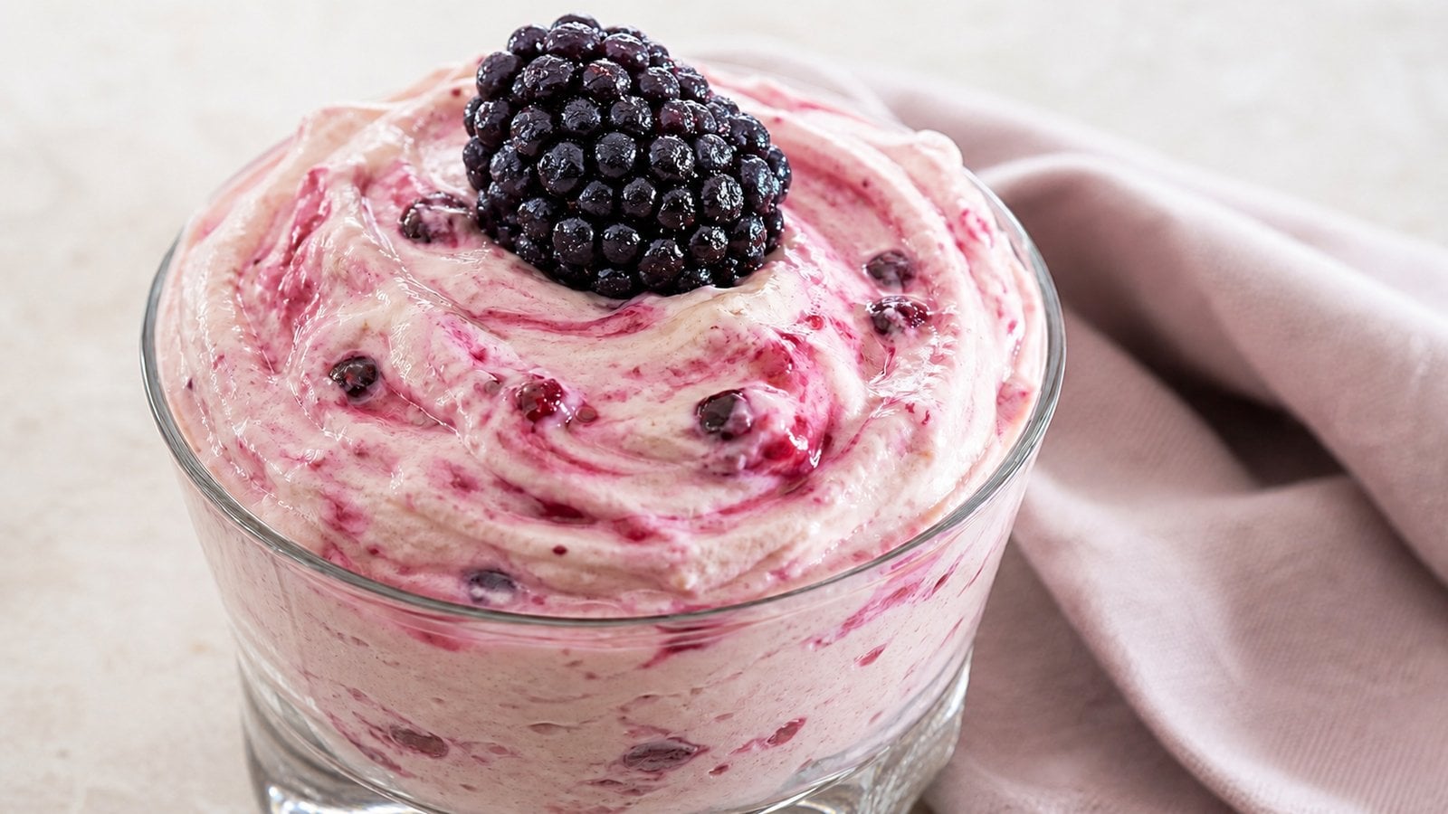 Close glass of pale pink cottage cheese berry mousse showing its creamy texture and berry flecks