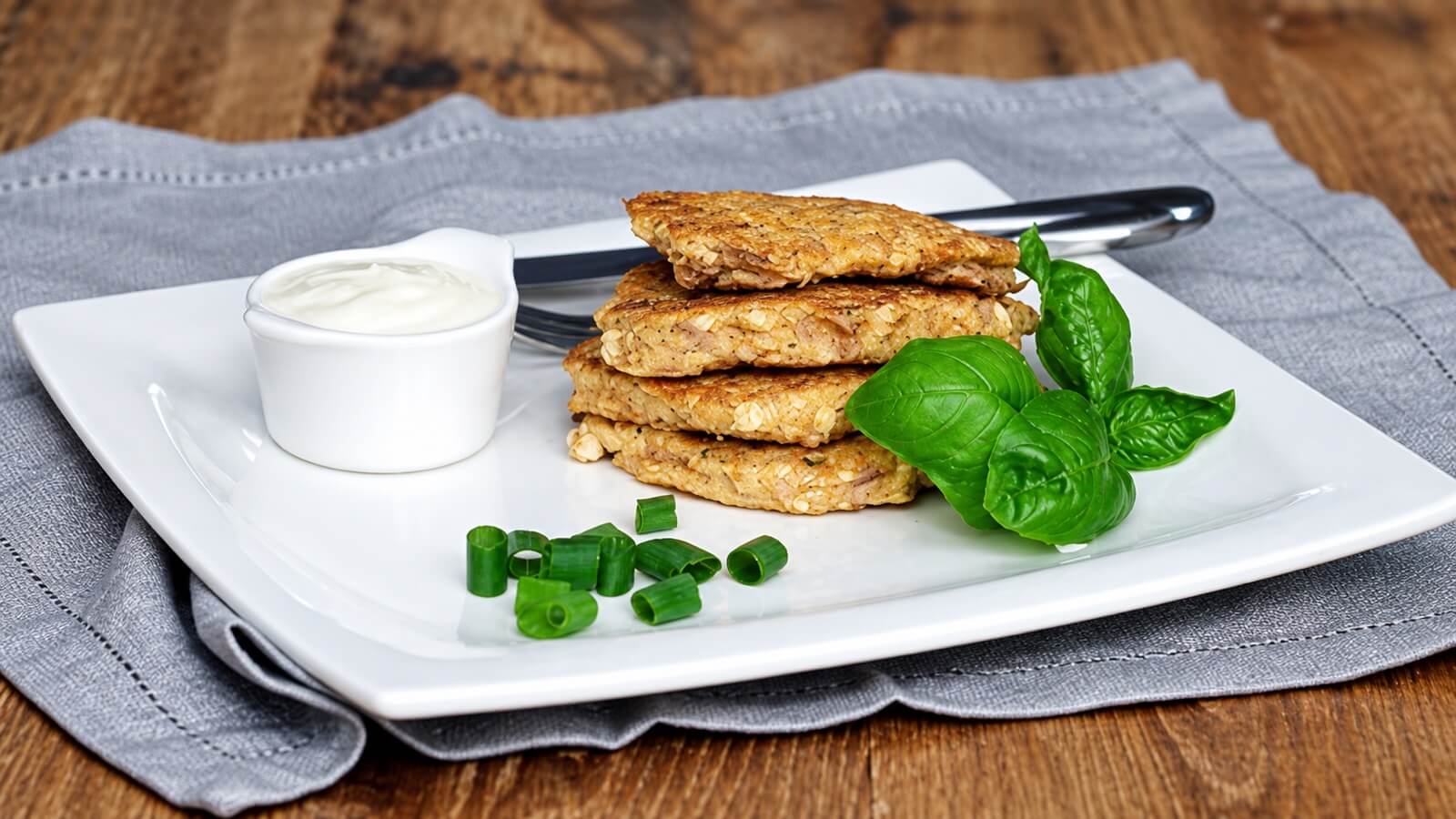 Savory oatmeal tuna pancakes with a side of sauce and herbs