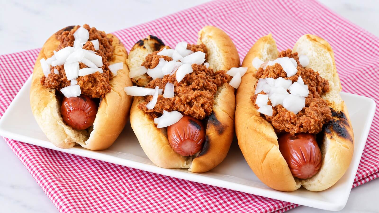 Three turkey chili dogs topped with chili and chopped onion